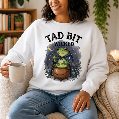 Tad Bit Wicked Frog Witch Sweatshirt – Whimsical Cauldron Halloween Sweater, Cute Spooky Season Gift for Her mockup-held-6a8e522f6874ebd7ebdd7117.png